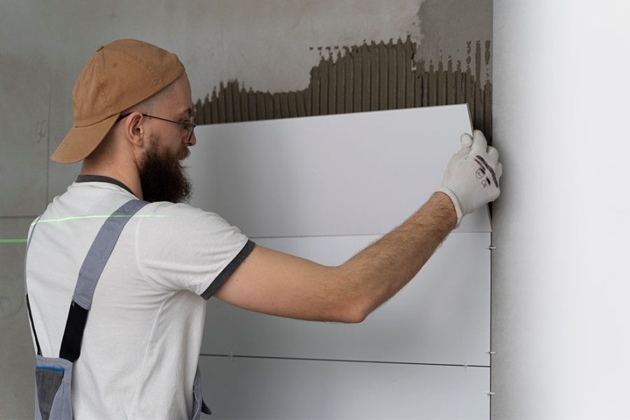 um trabalhador instalando o gesso acartonado em uma das paredes do edifício 