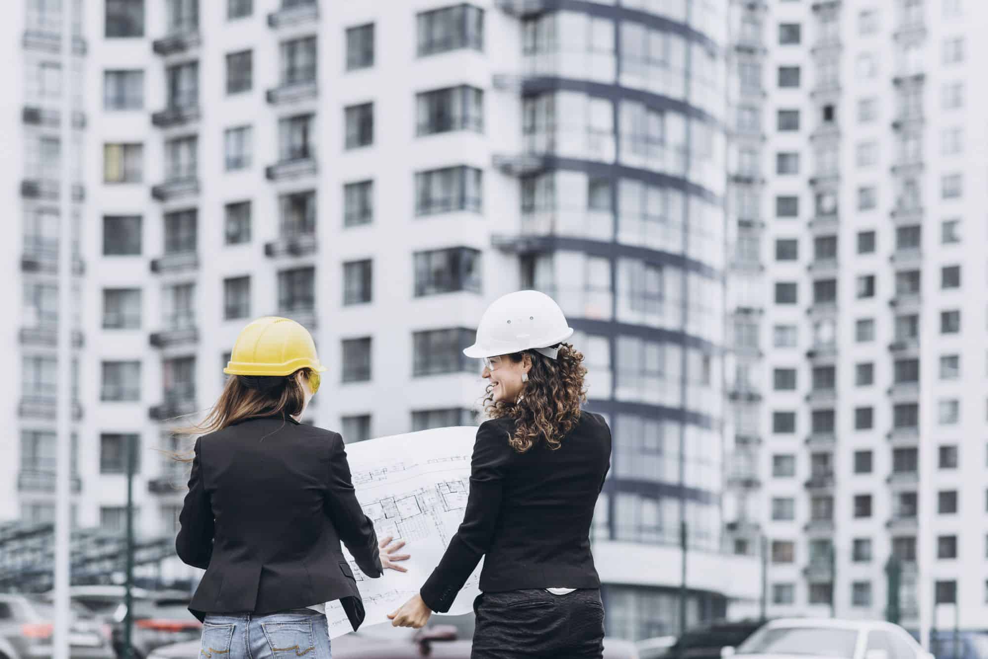 duas mulheres com capacete em uma obra