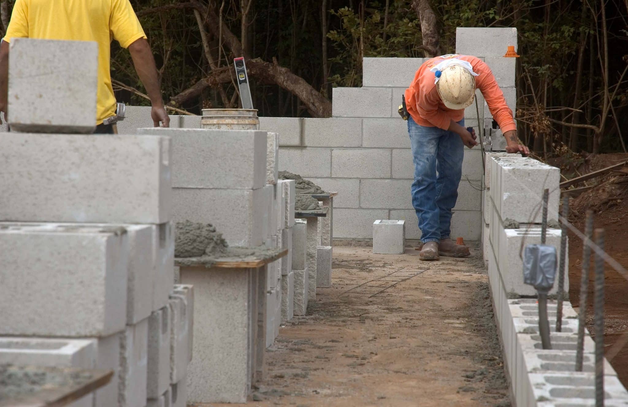 Operário assentando blocos em canteiro de obras