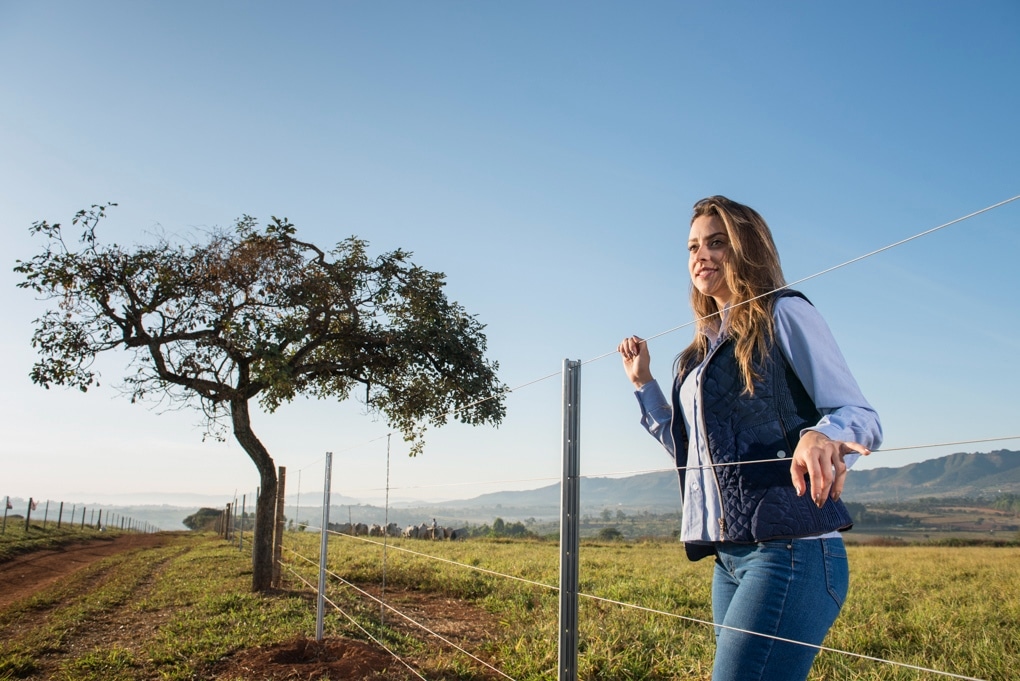 mulher olhando para o campo apoiada em uma cerca de arame