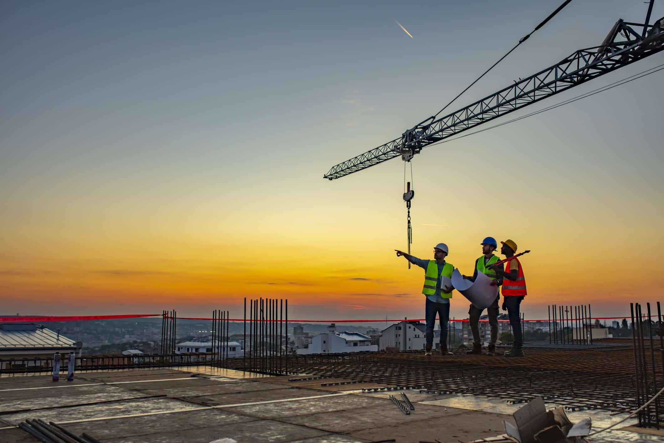 Engenheiros discutindo a obra abaixo de uma grua